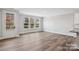 Bright living room featuring luxury vinyl plank flooring and large windows with a glimpse of the kitchen at 143 Carriage Club Dr # 102, Mooresville, NC 28117