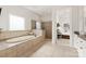 Bright bathroom showcasing a tiled tub, glass shower, and access to the main bedroom with a neutral color palette at 1506 Venetian Way Dr, Waxhaw, NC 28173