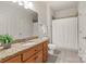 Clean bathroom with granite countertop, warm wood cabinets, large mirror, and a shower with white curtain at 1506 Venetian Way Dr, Waxhaw, NC 28173