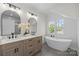 Bright bathroom featuring double vanities, soaking tub, and natural light from the window at 1824 Haines St, Charlotte, NC 28216