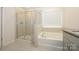 Modern bathroom with a separate shower and soaking tub under a window at 4242 Plumeria Way, Fort Mill, SC 29707