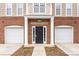 Townhome entrance with a black door, white columns, and two-car garages on either side at 6464 Park Pond Dr # 7, Charlotte, NC 28262
