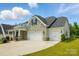 A beautiful house featuring a stone facade and a spacious driveway with a two-car garage at 6858 Hunts Mesa Dr, Fort Mill, SC 29707
