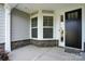 View of the front porch with stone accents, gray siding, a front storm door and manicured landscaping at 8716 Acadia Pkwy # 596, Sherrills Ford, NC 28673