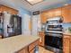 This kitchen features wood cabinets, a stainless steel refrigerator, and an island with a granite countertop at 10700 Summitt Tree Ct, Charlotte, NC 28277