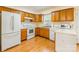 Well-lit kitchen with wooden cabinets, white appliances, and hardwood floors at 1461 Flintwood Dr, Rock Hill, SC 29732
