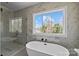 Modern bathroom featuring a soaking tub, window, glass enclosed shower, and marble tile at 1828 Haines St, Charlotte, NC 28216