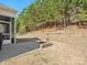 Large backyard with a concrete patio and retaining wall with trees and shrubs in the background at 1874 Larkspur Way, Tega Cay, SC 29708