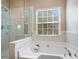 Bright bathroom featuring a soaking tub, separate glass-enclosed shower and large window bringing in natural light at 2020 Holly Villa Cir, Indian Trail, NC 28079