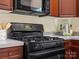 A black range is built into wood cabinets and topped with a microwave oven at 2020 Holly Villa Cir, Indian Trail, NC 28079