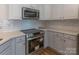 Close up of a kitchen featuring stainless steel appliances, white cabinets, quartz countertops, and wood-look flooring at 212 Mary Caroline Springs Dr, Mount Holly, NC 28120