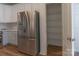 Close up of stainless steel refrigerator next to pantry in kitchen with white cabinets, quartz countertops, and wood-look flooring at 212 Mary Caroline Springs Dr, Mount Holly, NC 28120