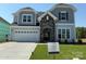 Charming two-story home featuring a stone-accented entryway, light-gray siding, and a two-car garage on a well-manicured lawn at 2204 Camber Dr # Cwo0076, Gastonia, NC 28054