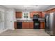 Modern kitchen with stainless steel appliances, wood cabinetry, and light-colored flooring at 8309 Knapp Ct, Locust, NC 28097