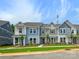 A view of several two-story townhomes with coordinated exteriors, lush lawns, and well-kept landscaping at 10113 Mamillion Dr, Huntersville, NC 28078