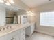 Bright bathroom featuring double sinks, white cabinetry, tile flooring, and glass block window for natural light at 123 Yellow Jacket Cir, Mooresville, NC 28117