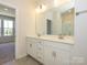 Bathroom showcasing double sinks with a large mirror, stone floors, and a glass-enclosed shower at 3928 Craig Ave, Charlotte, NC 28211