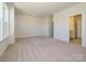 Bright, carpeted bedroom with neutral walls, a large window, and an ensuite bathroom with a door visible at 3928 Craig Ave, Charlotte, NC 28211