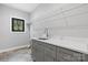 Bright laundry room featuring gray cabinets, white countertop, stainless steel sink, and window view at 6233 Riviera Run Estates Dr, Hickory, NC 28601