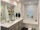 Bright bathroom with double vanity, soaking tub, white tile flooring, and decorative floral arrangement at 7711 Bainbridge Rd, Sherrills Ford, NC 28673