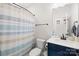 This half bath features a blue and tan striped shower curtain and a navy blue vanity with white sink at 118 Golden Trl, Mooresville, NC 28115