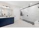 This primary bathroom has a navy blue vanity, a large walk-in shower with marble surround, and tiled floors at 118 Golden Trl, Mooresville, NC 28115