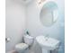 Powder room featuring a pedestal sink, round mirror, and modern toilet at 11907 Maria Ester Ct, Charlotte, NC 28277