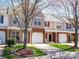 View of townhomes, showcasing individual garages, brick and siding, and attractive landscaping at 11907 Maria Ester Ct, Charlotte, NC 28277