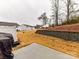 View of the backyard featuring a concrete patio and retaining wall with houses in the background at 1365 Eagle Claw Dr, Kannapolis, NC 28083