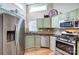 Modern kitchen with stainless steel refrigerator, ample counter space, stainless steel appliances and light green cabinets at 14021 Queens Harbor Rd, Charlotte, NC 28278