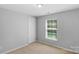 Bedroom with neutral carpet, light gray walls, and a window overlooking the front yard at 233 Proctor St, Gastonia, NC 28052