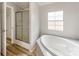 Bathroom featuring a soaking tub with tile surround and a shower with glass doors at 236 Sailwinds Rd, Mooresville, NC 28115