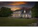 Charming two-story home with a large front yard, covered porch, and patriotic American flag waving in the breeze at sunset at 3929 Wexford Ln, Denver, NC 28037