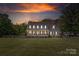 Charming two-story home with a covered porch, well-lit windows, and spacious front yard at sunset at 3929 Wexford Ln, Denver, NC 28037