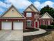 Charming two-story brick home featuring a two-car garage, red shutters, and manicured landscaping at 11124 Chastain Parc Dr, Charlotte, NC 28216