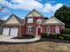 Charming two-story brick home featuring a two-car garage, red shutters, and manicured landscaping at 11124 Chastain Parc Dr, Charlotte, NC 28216