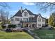 Rear view of a white house with a stone patio, a spiral staircase, a manicured lawn, and mature trees at 122 N Longfellow Ln, Mooresville, NC 28117