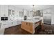 A bright kitchen with a large island, white cabinets, modern appliances, and dark hardwood floors at 122 N Longfellow Ln, Mooresville, NC 28117