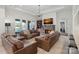 Inviting living room featuring a stone fireplace, leather sofas, coffered ceilings, and lake views at 122 N Longfellow Ln, Mooresville, NC 28117