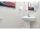 Modern powder room features a pedestal sink, elegant fixtures, decorative artwork and neutral colors at 137 Woodbridge Cir, Mount Holly, NC 28120