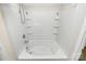 Relaxing soaking tub with built-in shelving, pristine white tiles, and a convenient showerhead for a spa-like experience at 137 Woodbridge Cir, Mount Holly, NC 28120