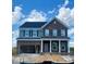 Two-story home featuring a brick facade, gray siding, a two-car garage, and a covered front porch, all under a blue sky at 13705 Roderick Dr # 194, Huntersville, NC 28078