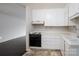 Galley kitchen featuring white cabinets, black appliances, and neutral-toned flooring at 1501 Fern Forest Dr, Gastonia, NC 28054