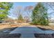 Large backyard with mature trees and a concrete pad for outdoor activities at 4210 Wrangler Sw Dr, Concord, NC 28027