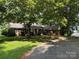 Charming brick home with lush trees, a curved driveway, and a welcoming front porch at 4210 Wrangler Sw Dr, Concord, NC 28027