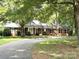 Charming brick home with lush trees, a curved driveway, and a welcoming front porch at 4210 Wrangler Sw Dr, Concord, NC 28027