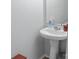 Close-up of a pedestal sink and mirror in a neutral-toned half bathroom with cleaning supplies at 4716 Meadowfield Rd, Charlotte, NC 28215