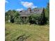 Exterior home view showing roof damage amid overgrown foliage in a grassy yard at 4724 Pottery Rd, Catawba, SC 29704