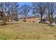 View of brick home exterior with spacious lawn and mature trees at 7047 Cheyenne Dr, Charlotte, NC 28262