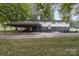 Backyard featuring a two-story home with a covered carport and a mix of grass and concrete at 7407 Forney Hill Rd, Denver, NC 28037